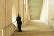 München-Botschafterin Laura Schieferle steht auf einer imposanten Steintreppe in einem Museum im Kunstareal.