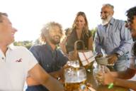 Drei Männer und zwei Frauen in einem Biergarten mit Bier und einer Picknicktasche auf dem Tisch in München.