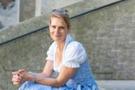 Carolin Engelhardt, die Gründerin und Creative Director „Münchner Dirndl“-Manufaktur, sitzt auf einer Treppe.