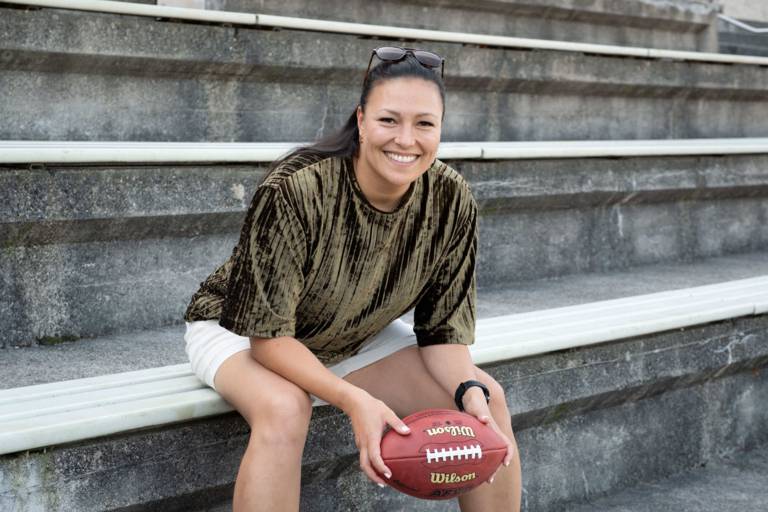 Nadine Nurasyid, die München Botschafterin für Football sitzt auf den Zuschauerrängen im Dantestadion und hält einen Football in ihren Händen.